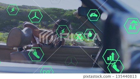 Leaning Indian woman in halter top out of convertible passing hillside with green hexagon icons Leaning Indian woman in halter top out of convertible passing hillside with green hexagon icons 135440813