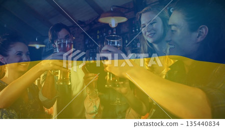Toasting five friends raising beer and wine glasses at bar counter with national flag overlay 135440834