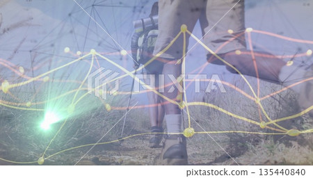 Leading hiker's lower legs walking on rural grassland trail, with hiking boots and network overlay Leading hiker's lower legs walking on rural grassland trail, with hiking boots and network overlay 135440840