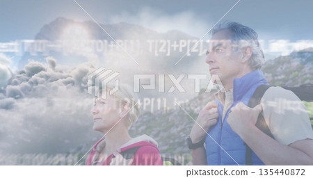 Standing couple gazing toward distant horizon on hillside with jackets, backpacks and code overlay Standing couple gazing toward distant horizon on hillside with jackets, backpacks and code overlay 135440872