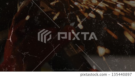 Grinding metal workpiece with angle grinder wearing gloves in workshop, throwing orange sparks Grinding metal workpiece with angle grinder wearing gloves in workshop, throwing orange sparks 135440897
