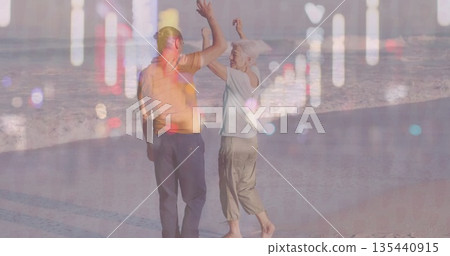 Dancing barefoot couple raising arms on wet beach sand, with sea waves reflections 135440915