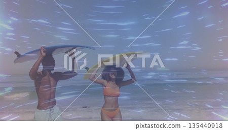 Walking couple carrying surfboards at sandy beach, feeling waves, wearing trunks and orange bikini 135440918