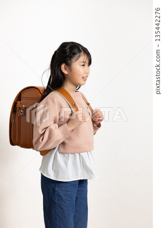 教室裡，一個帶著微笑的小學生女孩背著書包。 135442276
