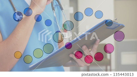 Nurse in blue scrubs reviewing notes on blue clipboard in clinic room, wearing stethoscope 135443013