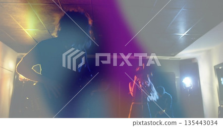 Performing musicians strumming guitars and singing on stage under colored lights, with mic stand Performing musicians strumming guitars and singing on stage under colored lights, with mic stand 135443034