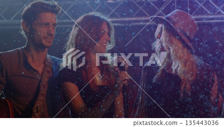 Singing female vocalist holding microphone on stage with truss, electric guitar and falling snow Singing female vocalist holding microphone on stage with truss, electric guitar and falling snow 135443036