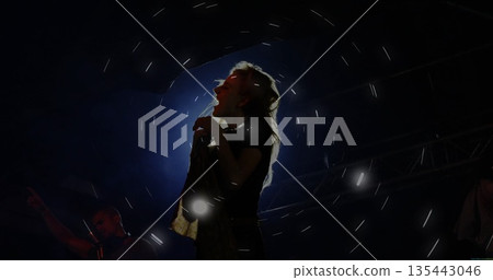 Singing backlit singer holding microphone stand on music venue stage, with fog and metal trusses Singing backlit singer holding microphone stand on music venue stage, with fog and metal trusses 135443046