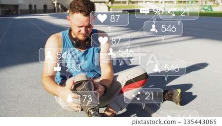 Adjusting prosthetic leg, man sitting on blue track wearing sportswear, floating social media icons Adjusting prosthetic leg, man sitting on blue track wearing sportswear, floating social media icons 135443065