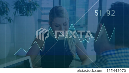 Reviewing woman analyzing data on laptop by windows in office, with digital line chart overlay Reviewing woman analyzing data on laptop by windows in office, with digital line chart overlay 135443070