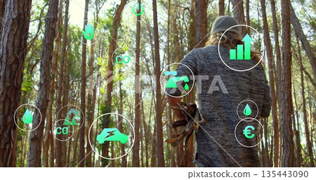 Walking adult male carrying firewood through pine forest with digital energy icons, copy space Walking adult male carrying firewood through pine forest with digital energy icons, copy space 135443090