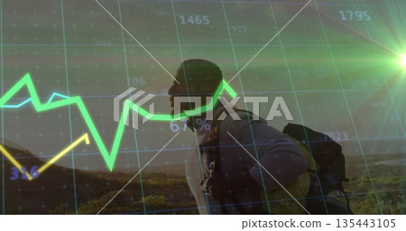 Hiking man in jacket and backpack through hilly terrain at sunrise, with financial chart overlay 135443105