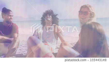 Smiling and laughing four friends sitting on sandy shoreline, with red framed sunglasses and towel Smiling and laughing four friends sitting on sandy shoreline, with red framed sunglasses and towel 135443149