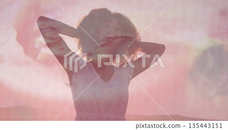 Raising arms behind head, woman standing at sunset over hills, with white lace dress, lens-flare Raising arms behind head, woman standing at sunset over hills, with white lace dress, lens-flare 135443151
