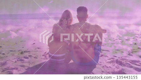 Sitting couple wearing blue trunks and striped bikini on sandy beach, with ocean waves and horizon Sitting couple wearing blue trunks and striped bikini on sandy beach, with ocean waves and horizon 135443155