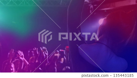 Performing female artist raising arm on stage with lighting fixtures and smartphones, copy space 135443185