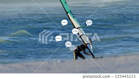 Adjusting windsurf sail to board, male in wetsuit on sandy shoreline with rigging lines, copy space Adjusting windsurf sail to board, male in wetsuit on sandy shoreline with rigging lines, copy space 135443215