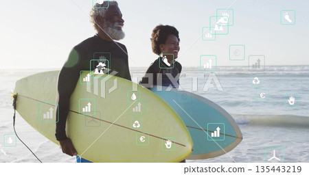 Standing couple wearing wetsuits and holding surfboards at beach, featuring light blue and yellow 135443219