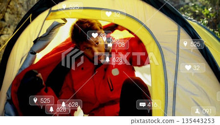 Camper wearing red jacket pulling back yellow tent flap in forest campsite, with floating AR icons Camper wearing red jacket pulling back yellow tent flap in forest campsite, with floating AR icons 135443253