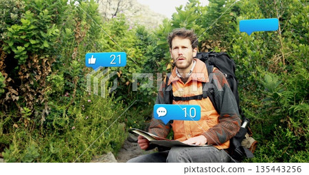 Examining unfolded map male hiker with black backpack on rocky forest trail, with social icons 135443256