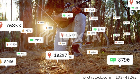 Kneeling tactical operative scanning forest floor in pine woods, with rifle and data overlays Kneeling tactical operative scanning forest floor in pine woods, with rifle and data overlays 135443262