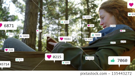 Reclining woman reading book in green hammock among sunlit pine trees, with social media icons Reclining woman reading book in green hammock among sunlit pine trees, with social media icons 135443272