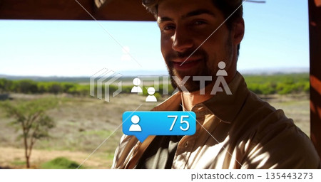 Shirt-wearing man taking selfie on veranda over plain, with blue 75-notification bubble, copy space 135443273