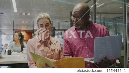 Collaborating senior man in maroon shirt and woman in peach blouse reviewing folder at office space Collaborating senior man in maroon shirt and woman in peach blouse reviewing folder at office space 135443341