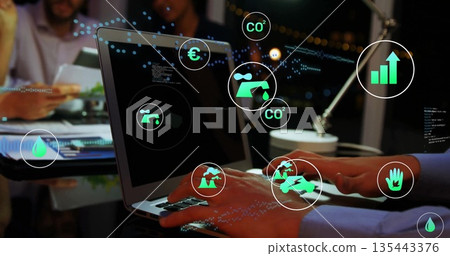 Typing pair of hands pressing laptop keys at office conference table, with eco icons overlay 135443376