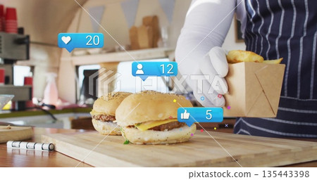 Vendor in striped apron placing items in box at food truck, with cheeseburgers board social icons 135443398
