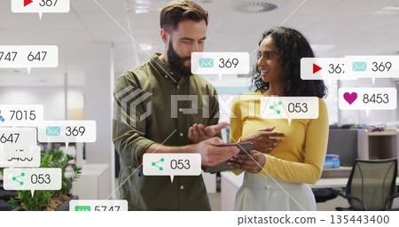 Reviewing coworkers in casual attire analyzing metrics on tablet in office with metric overlays Reviewing coworkers in casual attire analyzing metrics on tablet in office with metric overlays 135443400