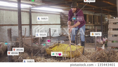 Leaning adult farmer holding rope over yellow feeding tub in rustic barn, with social media icons 135443401