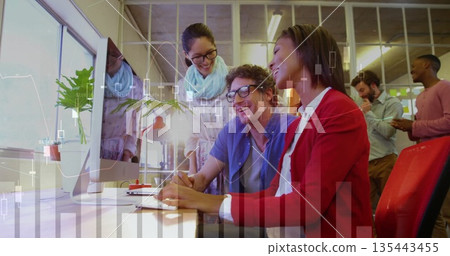 Leaning three colleagues analyzing financial charts on monitor in open plan office, with smartphone 135443455