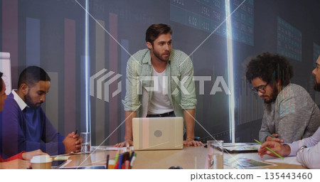 Leaning man in green shirt guiding discussion in conference room, with laptop and printed charts Leaning man in green shirt guiding discussion in conference room, with laptop and printed charts 135443460
