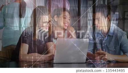 3 colleagues collaborating at wooden table in office, with silver laptop metal framed glass panels 3 colleagues collaborating at wooden table in office, with silver laptop metal framed glass panels 135443495