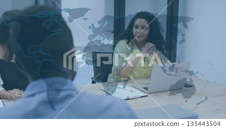 Leading curly-haired woman in yellow blouse addressing team at boardroom with laptop and papers Leading curly-haired woman in yellow blouse addressing team at boardroom with laptop and papers 135443504