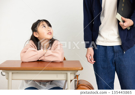 一位男老師和一位小學生在教室裡交談 135443865