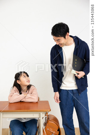 一位男老師和一位小學生在教室裡交談 135443868