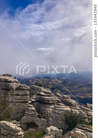 A mystical morning walk through the rocky landscapes of Torcal de Antequera in Andalusia, Spain, as soft mist drifts under the gentle rays of the sun. 135443949
