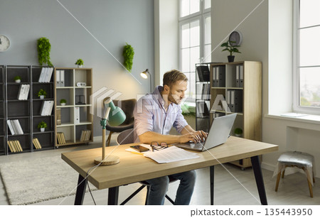 Workaholic man working late with laptop on online project at office desk in night 135443950