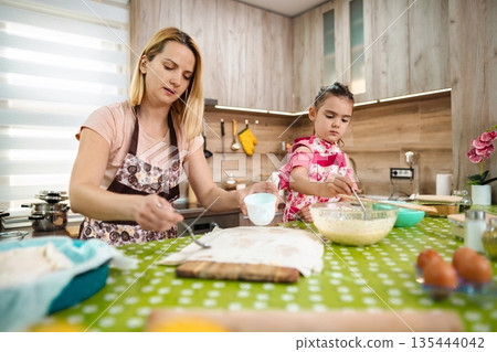 Baking delights in a cozy kitchen with mother and daughter Baking delights in a cozy kitchen with mother and daughter 135444042