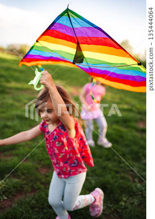 Children joyfully flying a colorful kite on a sunny afternoon 135444064