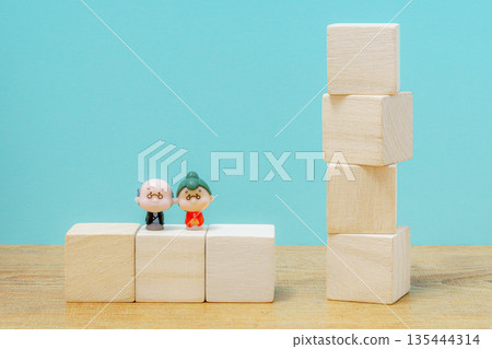 Miniature dolls of an elderly couple standing next to building blocks Miniature dolls of an elderly couple standing next to building blocks 135444314