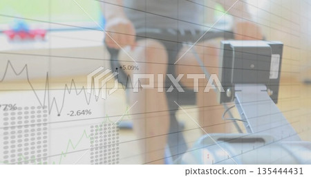 Adult male in sportswear pulling rowing handle on rail in fitness studio, with data graph overlay Adult male in sportswear pulling rowing handle on rail in fitness studio, with data graph overlay 135444431