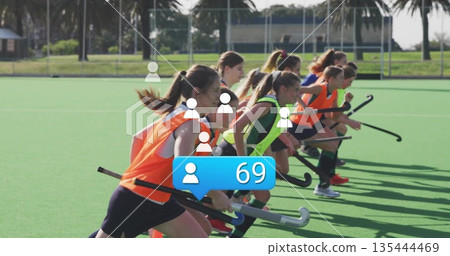 Leaning hockey players wearing fluorescent bibs and holding sticks on turf bordered by palm trees Leaning hockey players wearing fluorescent bibs and holding sticks on turf bordered by palm trees 135444469