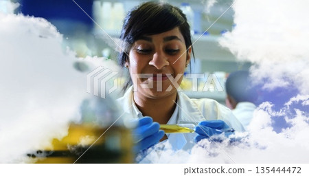 Scientist wearing lab coat gloves transferring yellow liquid with pipette into test tube at lab Scientist wearing lab coat gloves transferring yellow liquid with pipette into test tube at lab 135444472
