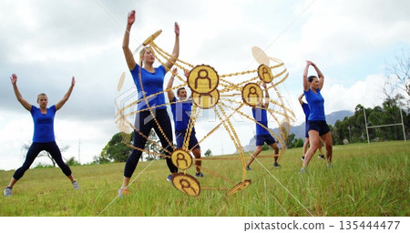 Six adults wearing blue tops black pants stretching on grassy field, with golden orb and goalposts Six adults wearing blue tops black pants stretching on grassy field, with golden orb and goalposts 135444477