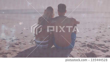 Leaning romantic couple embracing on sandy shore, with swimwear, ocean horizon and footprints Leaning romantic couple embracing on sandy shore, with swimwear, ocean horizon and footprints 135444528
