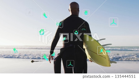 Standing surfer wearing black wetsuit holding yellow surfboard on beach, with floating eco icons Standing surfer wearing black wetsuit holding yellow surfboard on beach, with floating eco icons 135444551