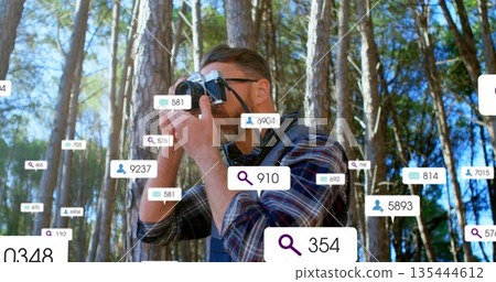 Standing man raising mirrorless camera in sunlit pine forest, with eyeglasses and data overlays Standing man raising mirrorless camera in sunlit pine forest, with eyeglasses and data overlays 135444612